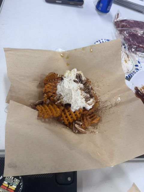 A sweet waffle fry dessert topped with whipped cream, served on parchment.